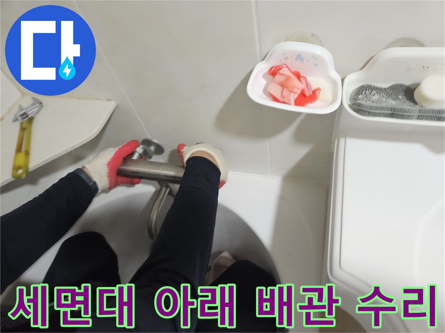 몽키스패너로 세면대 하단 수도 연결 부위를 조이는 누수 보수 장면