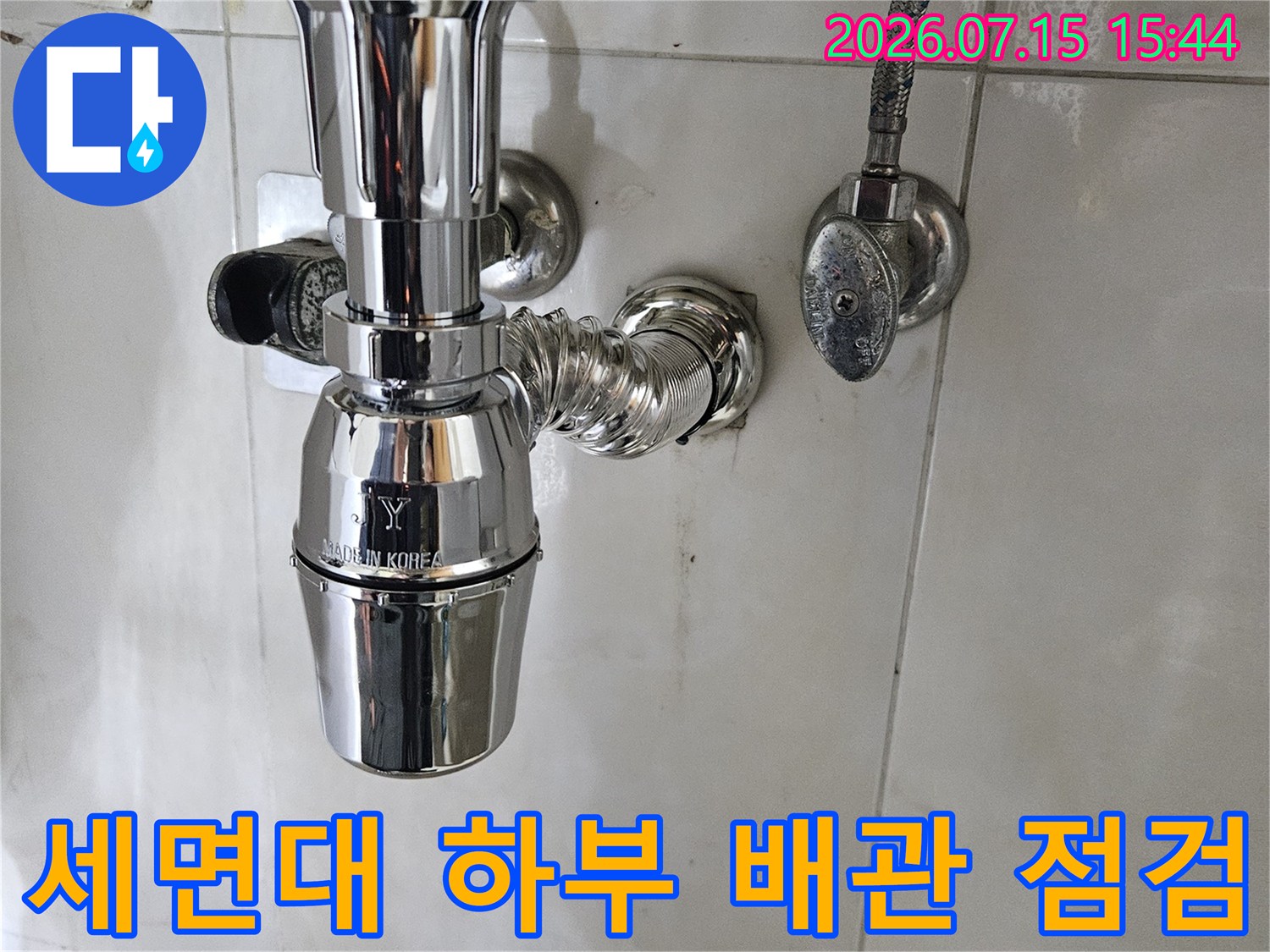 세면대 아래쪽 노출된 금속 배관과 연결 부위를 정밀하게 점검하는 모습