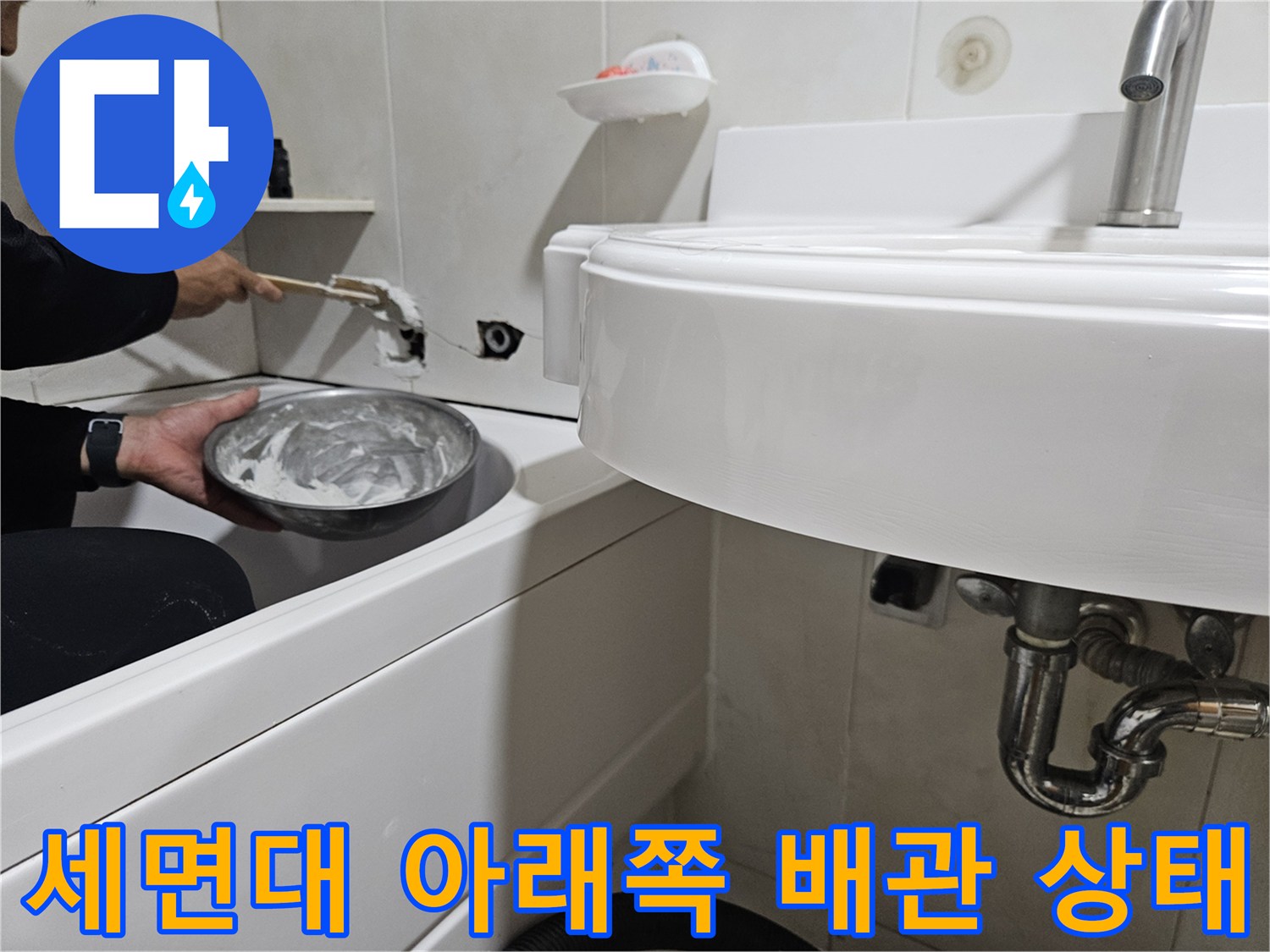 세면대 하단 배관 및 주변 타일 부위를 점검 중인 사진