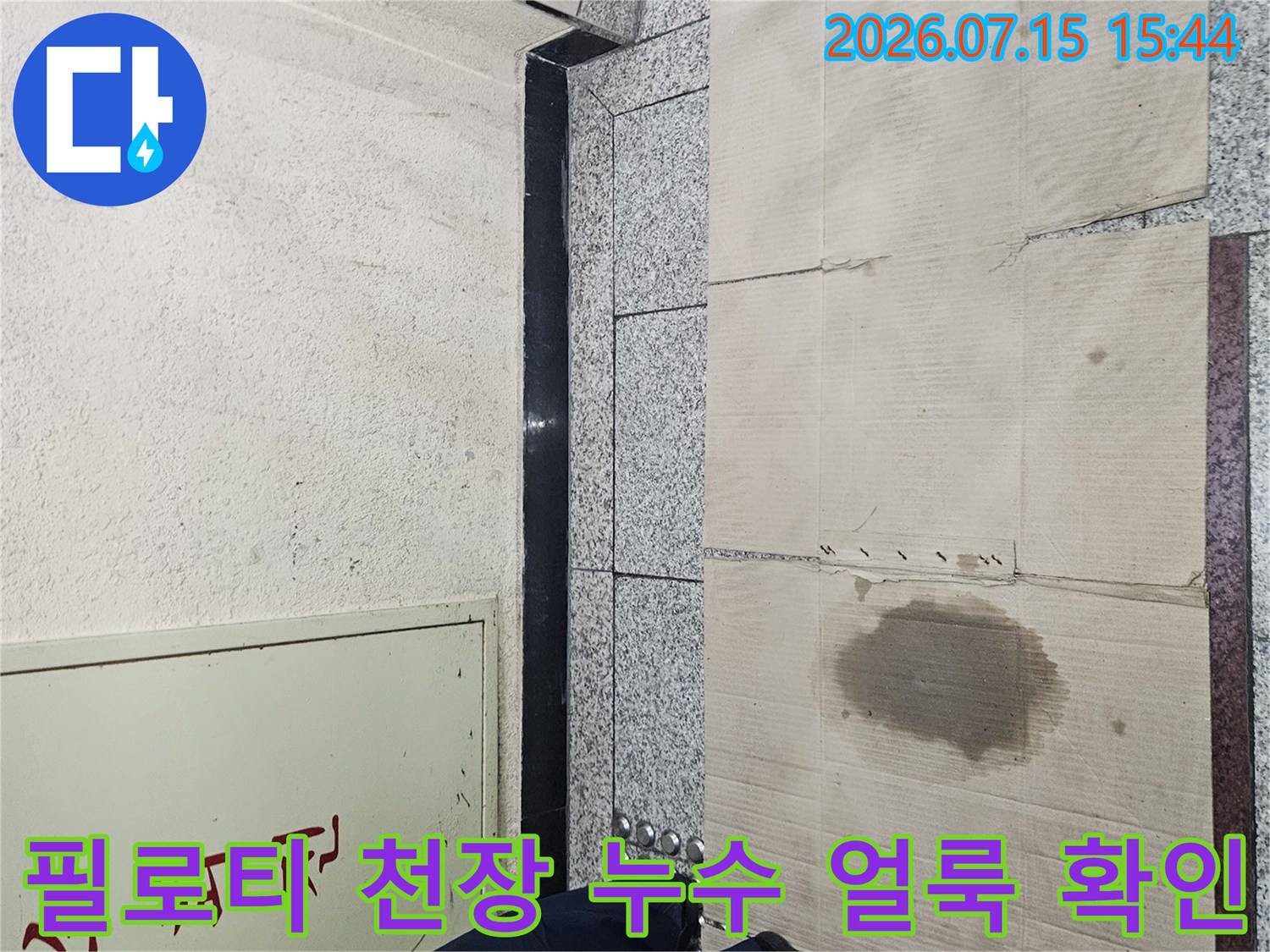 필로티 천장의 나무판넬 위에 발생한 노란색 누수 흔적과 작업자의 신발이 보이는 현장 사진