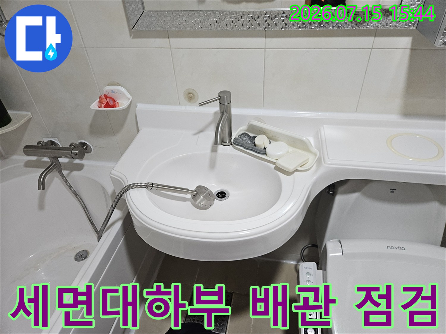 화장실 세면대 하부의 노출된 배관과 수전 부위를 상세히 점검하는 모습