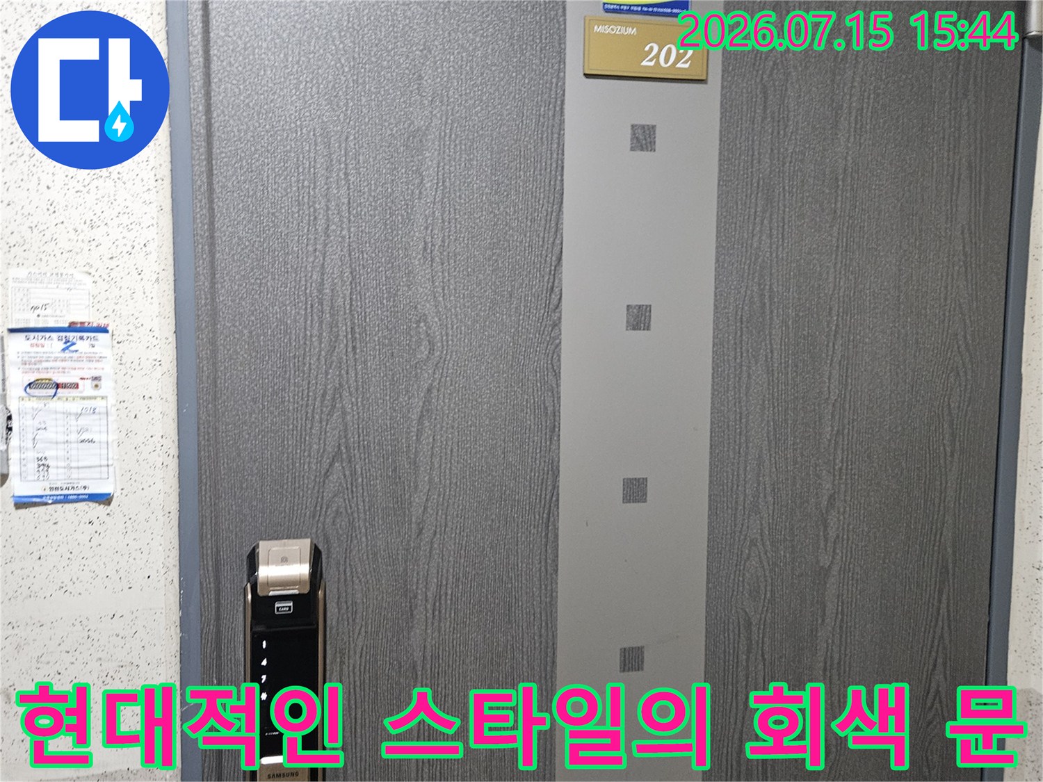 회색 바탕에 텍스처가 가미된 출입문과 스마트 도어록 장치