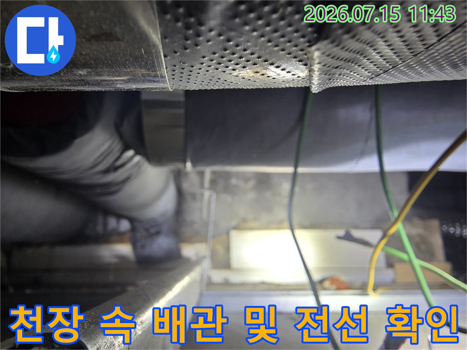 좁은 천장 공간에서-보온 배관과 전기선을 점검하는 엔지니어의 모습