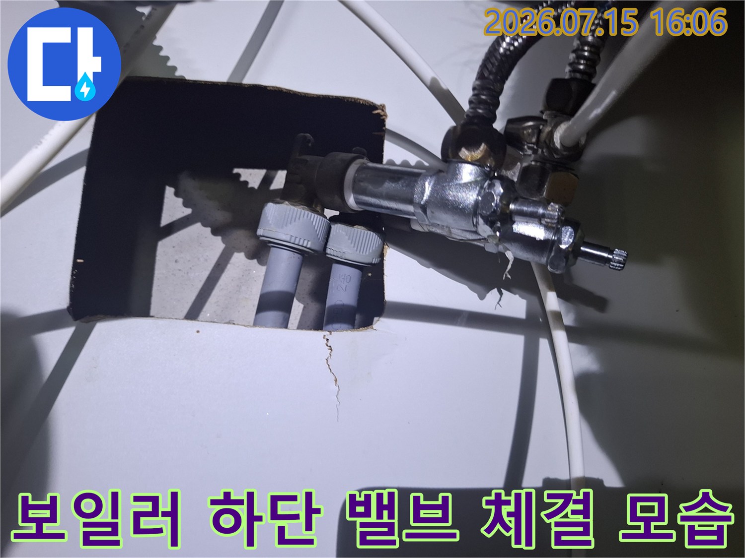 금속제 컨트롤 밸브와 흰색 배관이 연결된 보일러 하단 설비의 세부 모습