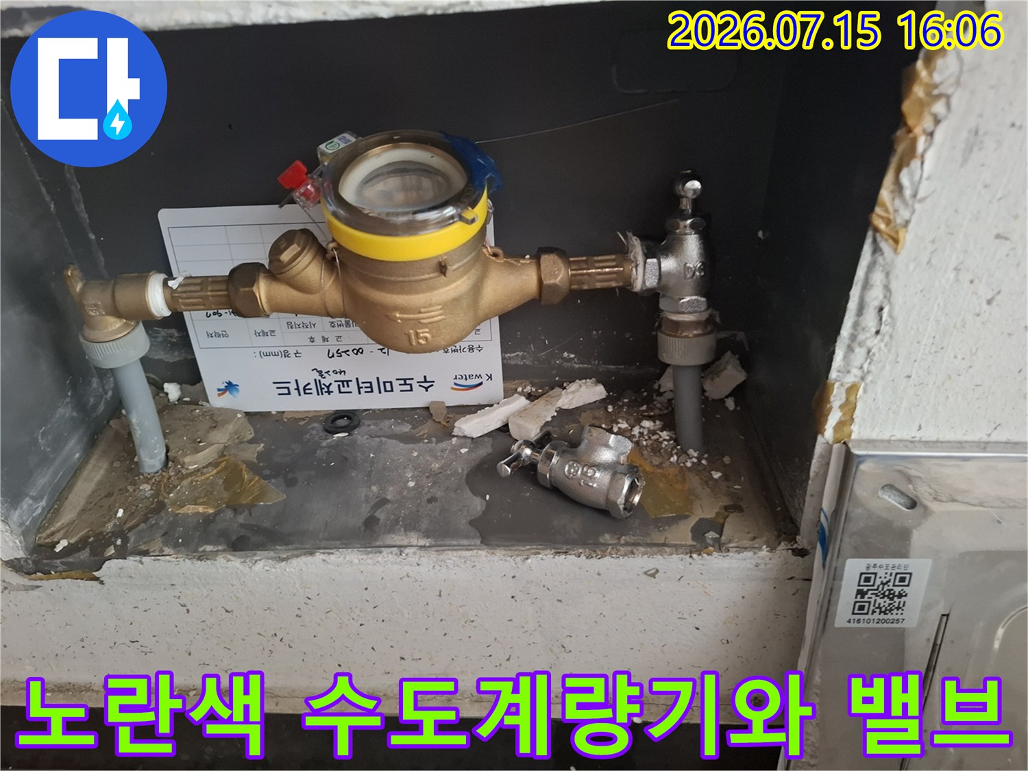 회색 함 내부에 설치된 금속-수도계량기와 연결 밸브의 사진