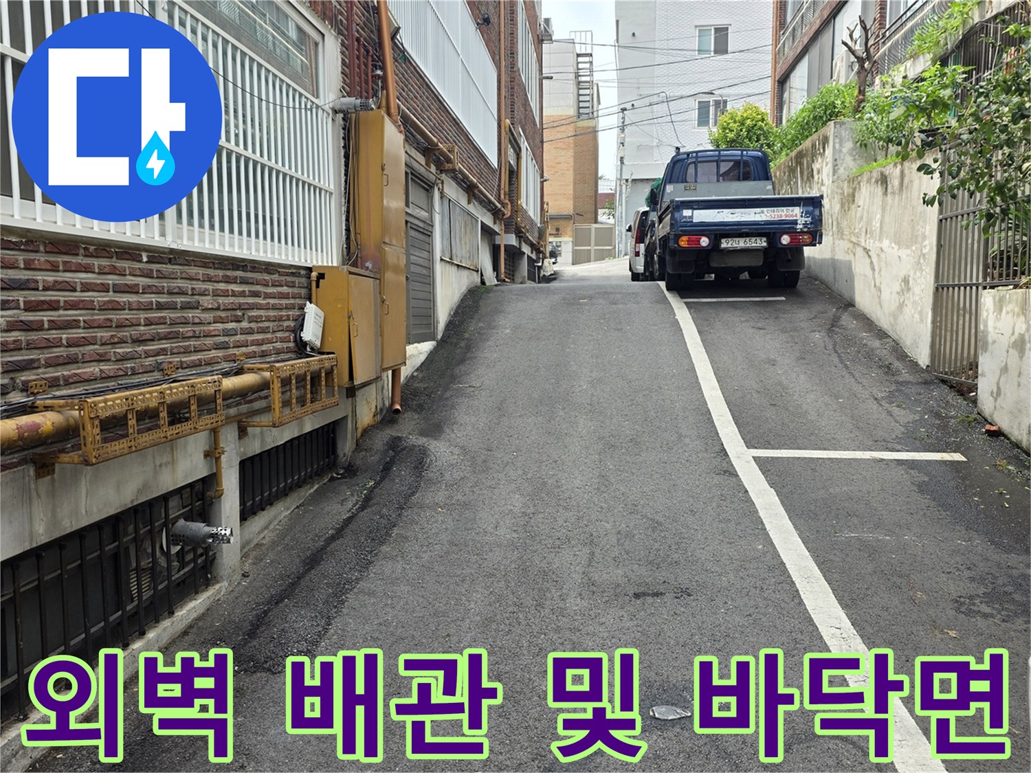 건물 외벽의 노란색 배관과 아래쪽 금속 마감재 부위입니다.