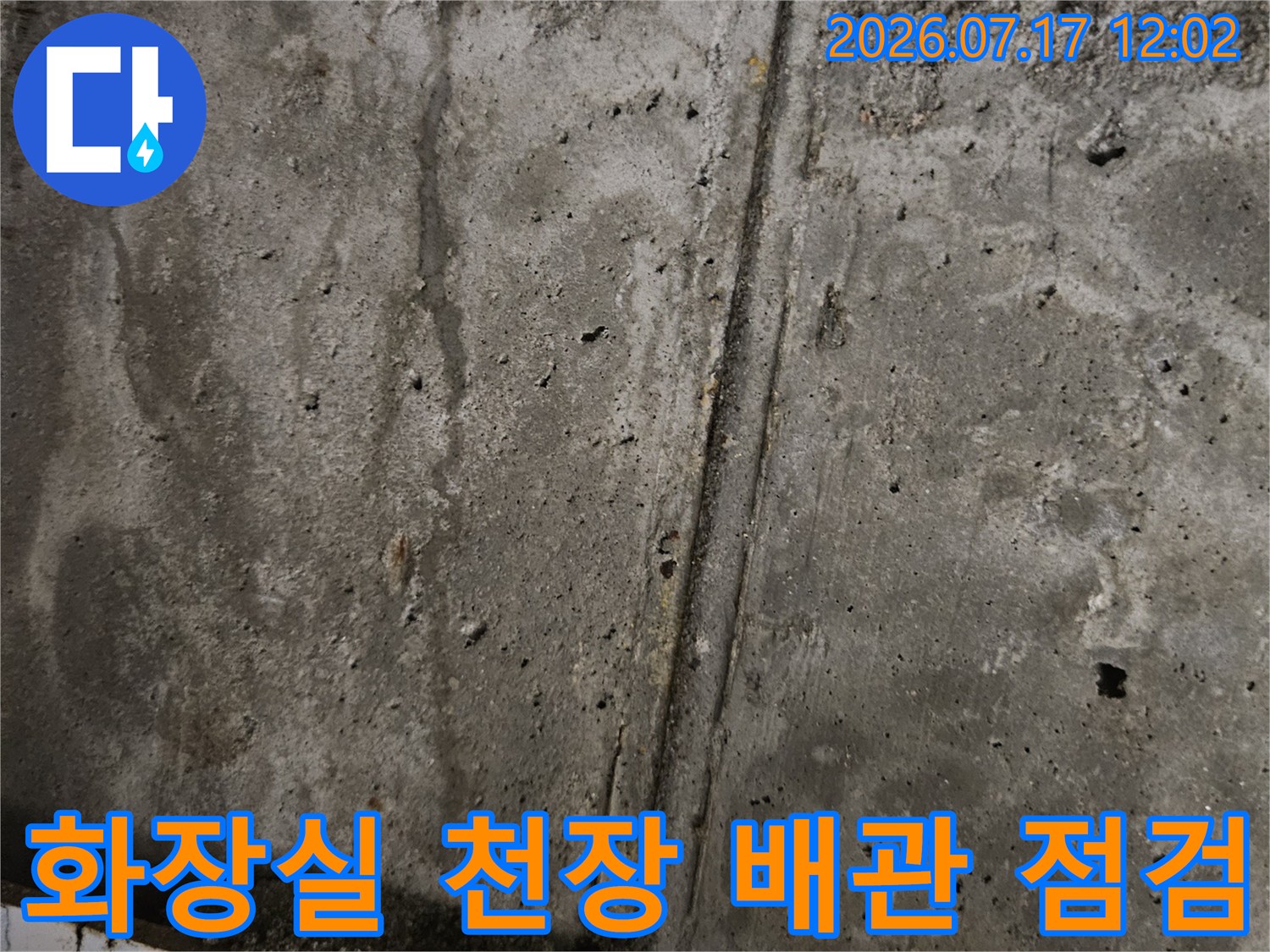 화장실 천장 내부의 노출된 콘크리트 면과 배관 연결 부위를 정밀하게 점검하는 모습