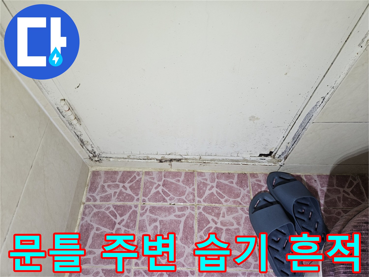 화장실 입구 문틀 하단의 곰팡이와 습기에 의한 변색 부위