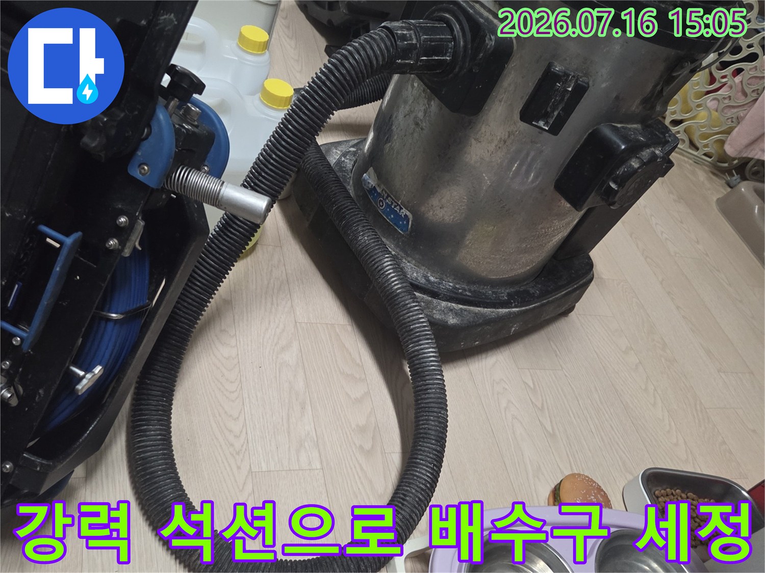 석션 장비를 연결하여 싱크대 하부 배관 내 슬러지와 이물질을 강하게 빨아들이는 장면