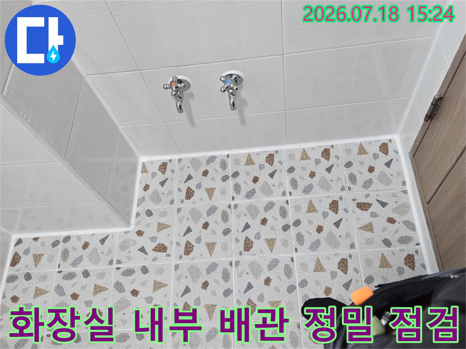 화장실 벽면 타일과 수전부의 노출된 배관 구조를 촬영한 모습