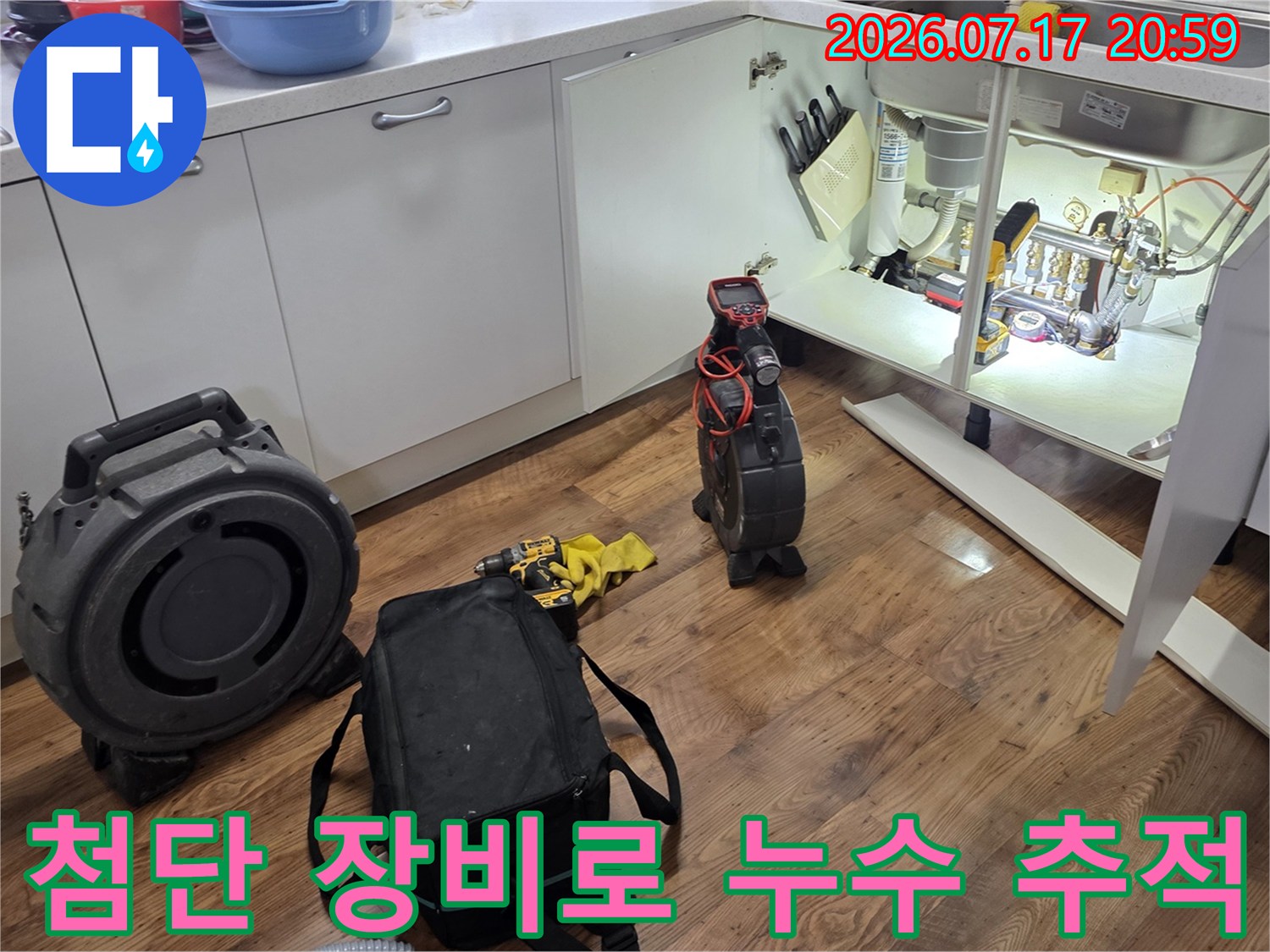 싱크대 하부에 여러 측정 기구를 배치하여 배출용 배관의 이상 여부를 다각도로 점검하는 장면
