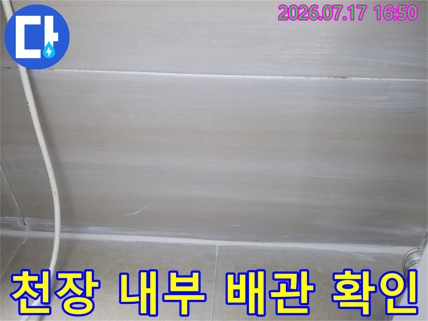 노출된 천장 공간 내의 배관과 벽면 상태를 조사하는 장면