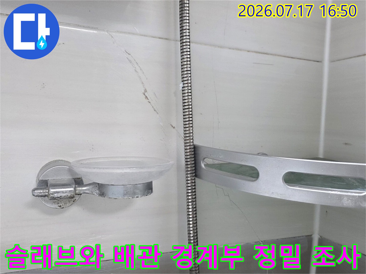 화장실 천장 안쪽에서 노출된 금속 배관과 주변 슬래브의 상태를 조사하는 모습