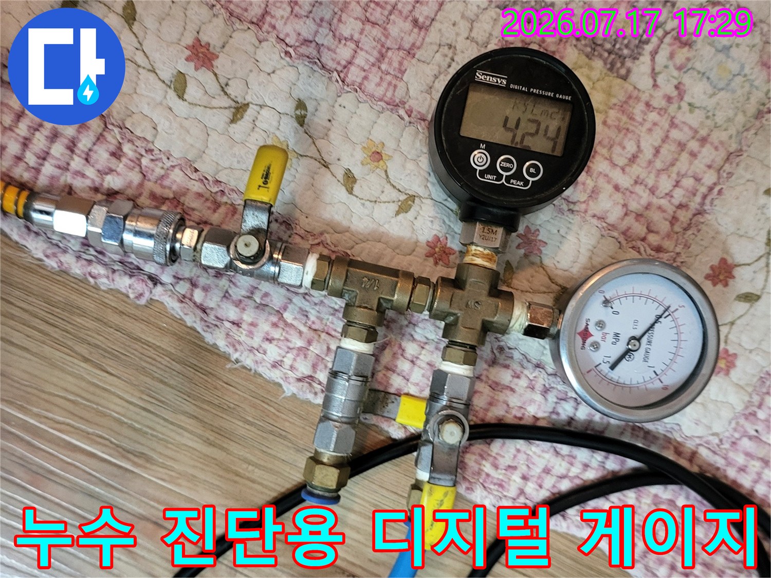 파란색 호스와 금속 밸브가 연결된 정밀 압력 측정 장비의 근접 사진