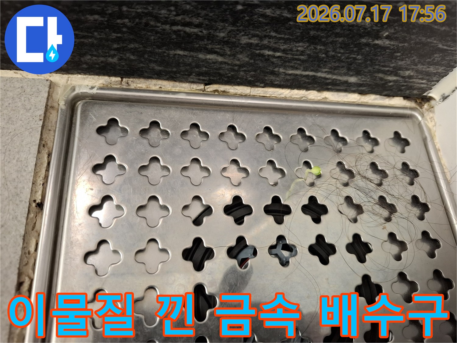 스테인리스 재질의 욕실 배수구-오염물이 끼어 있는 근접 사진