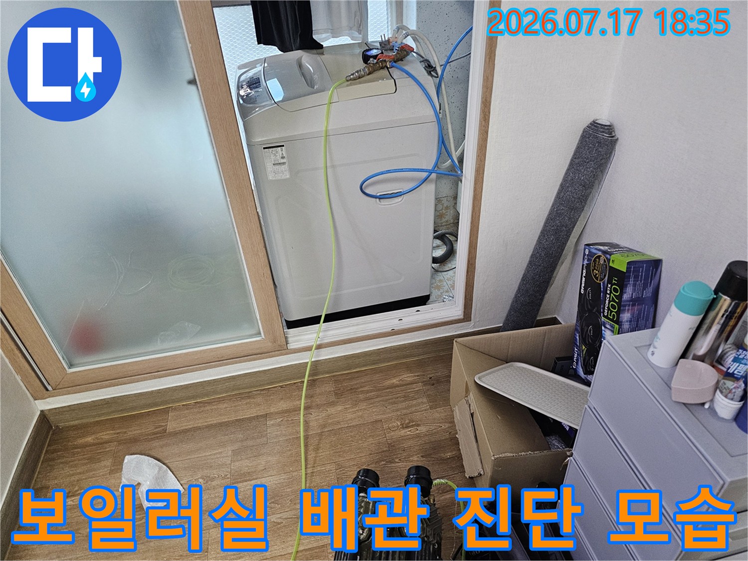흰색 보일러 본체에 파란색과 노란색 배관 호스가 복잡하게 연결되어 있는 장면