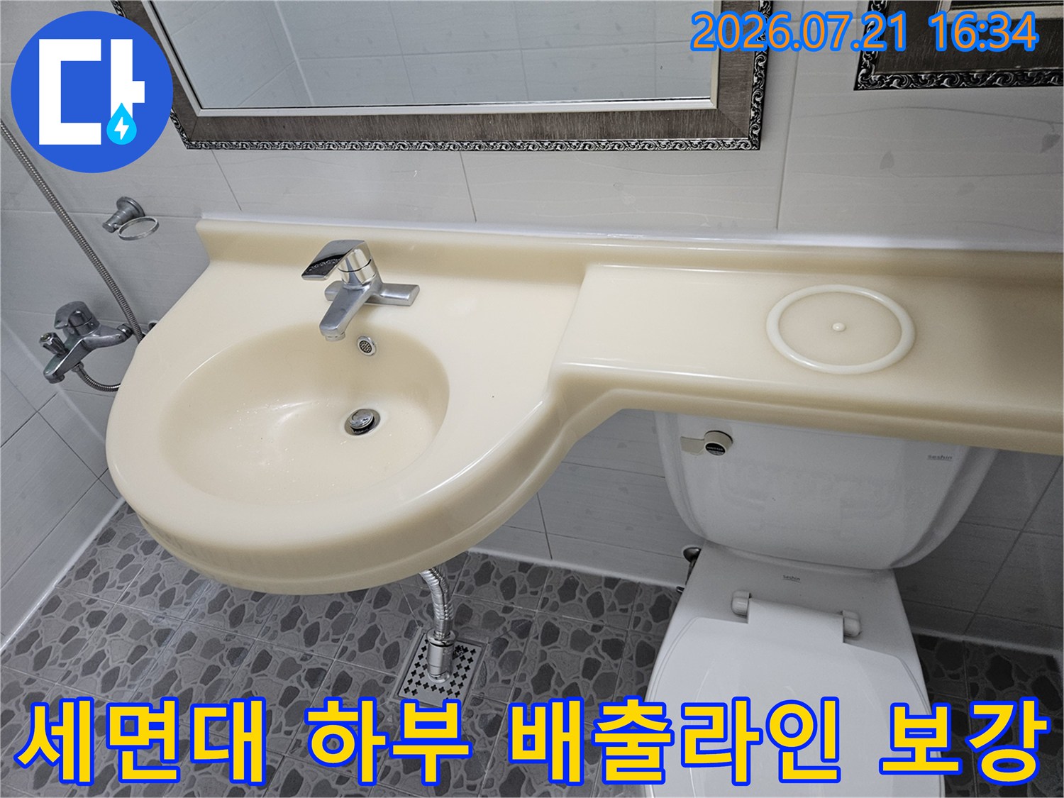 화장실 세면대 밑쪽과 바닥 유가 연결 구간을 꼼꼼하게 점검하고 있는 모습