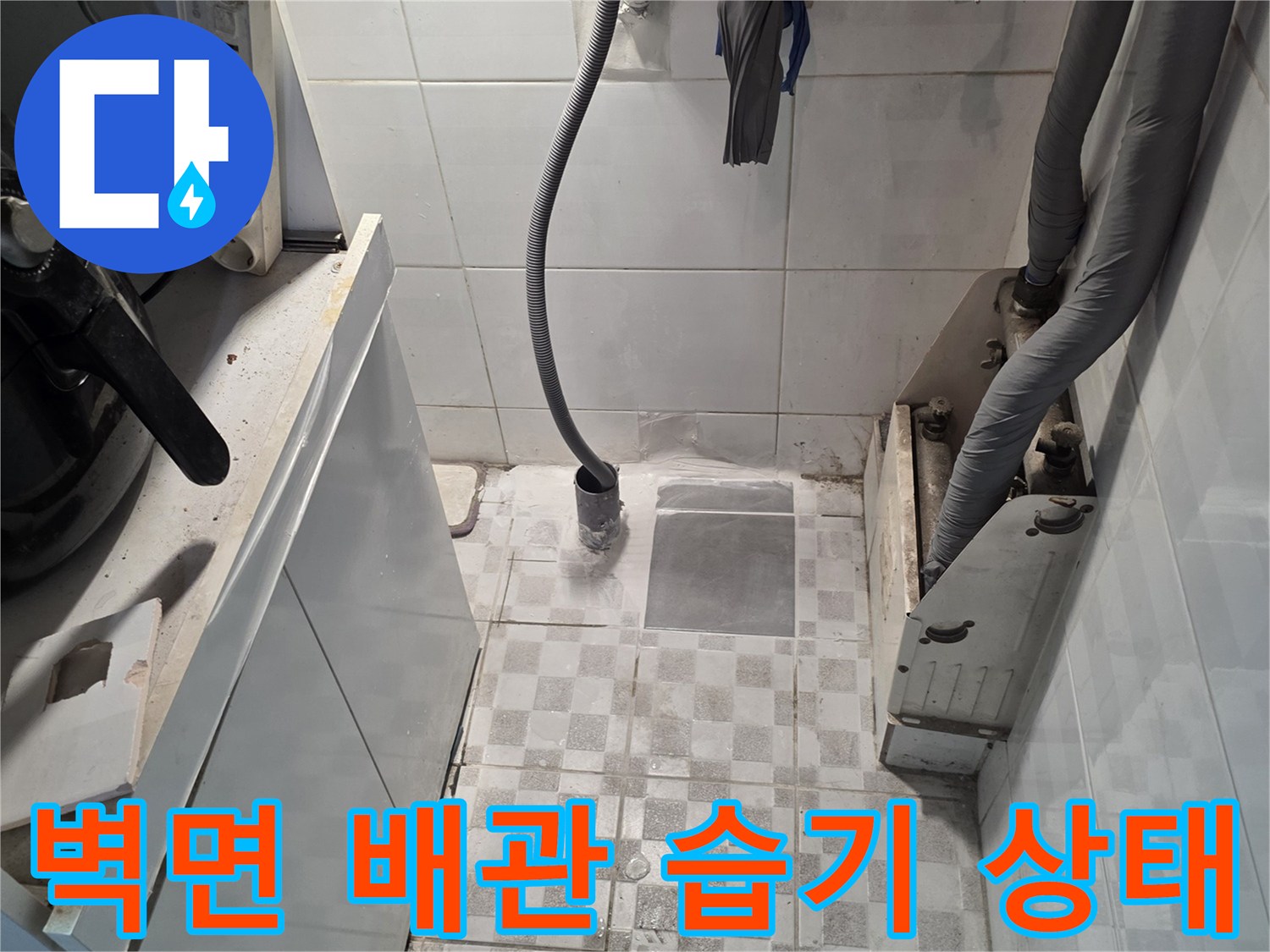 습기로 인해 변색된 벽면 타일과 노출된 배관 연결부