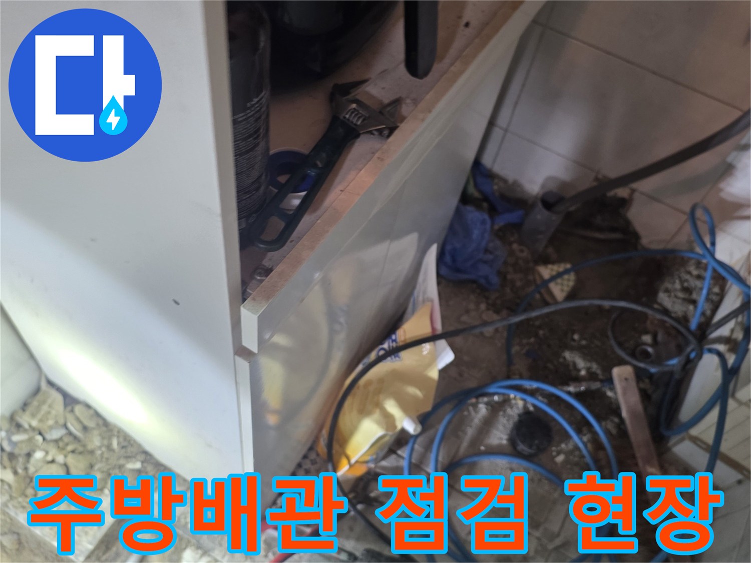 싱크대 하단 작업 공간의 복잡한 배관과 장비 모습