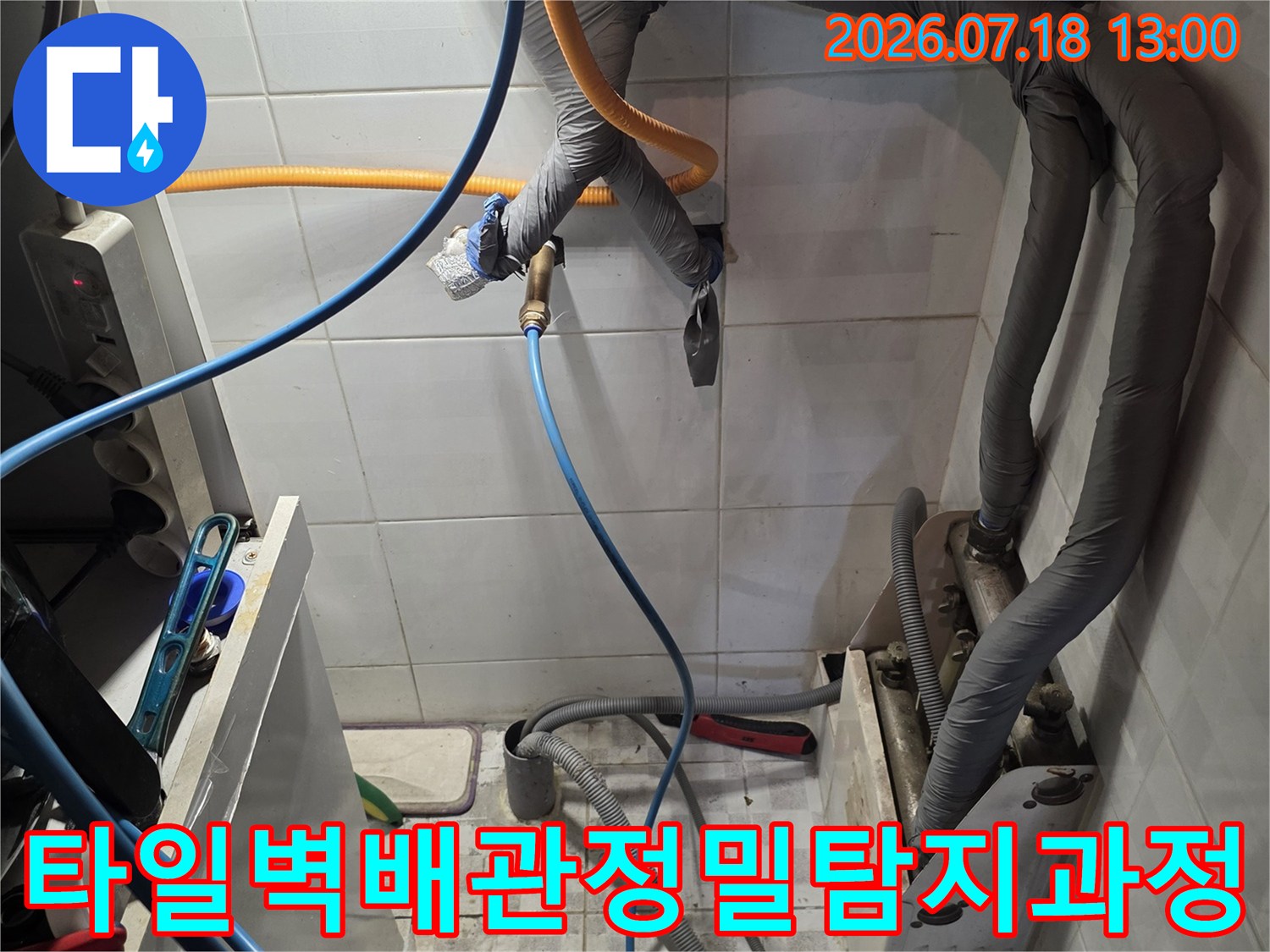 회색 보온재로 덮인 벽면 배관에 노란색과 파란색 탐지 호스가 연결된 현장 사진