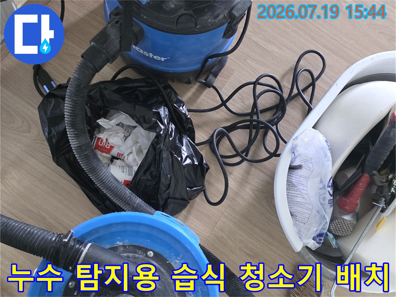 바닥에 놓인 파란색 진공 흡입기와 공구함-누수 점검을 위한 준비 단계