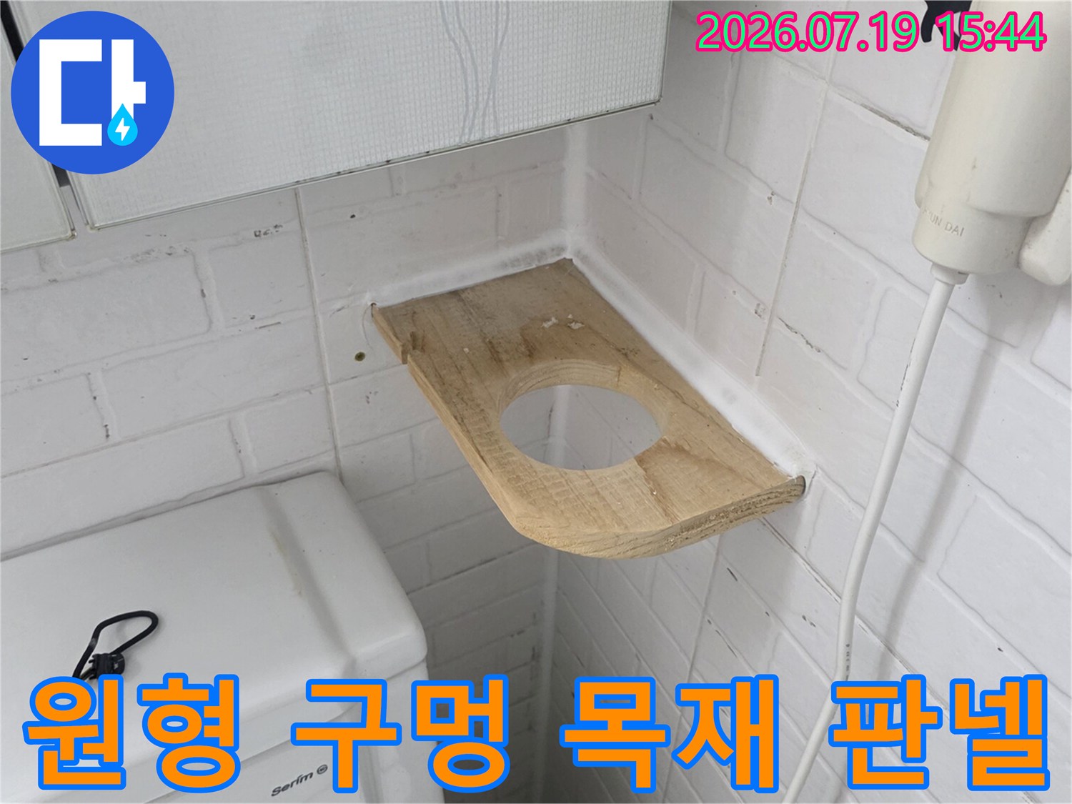 화장실 흰색 벽돌 모양 타일과-나무 소재의 배관 점검판이 설치된 모습