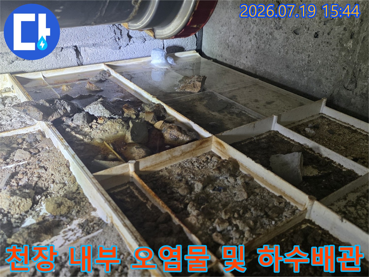 흰색 판넬 위에-쌓인 누수 찌꺼기와 상단 검정 배관의 모습