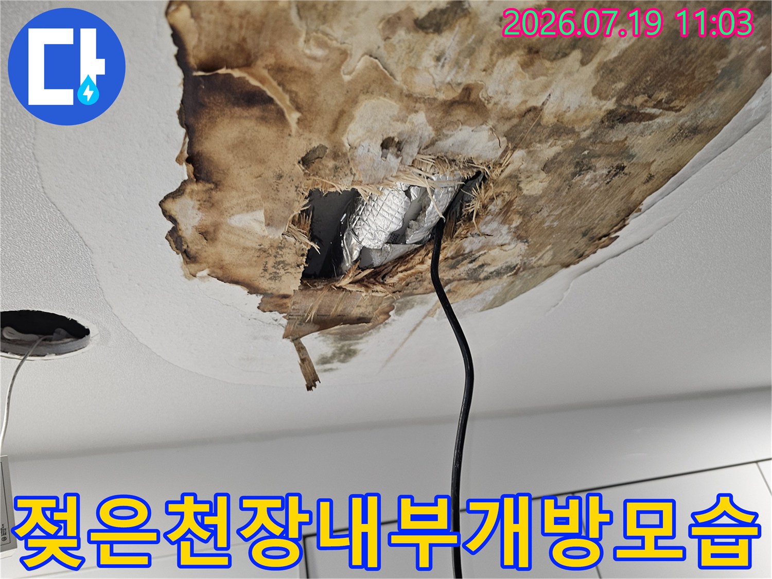 갈색으로 오염된 천장 마감재와 절개된 틈 사이의 은색 보온재 사진