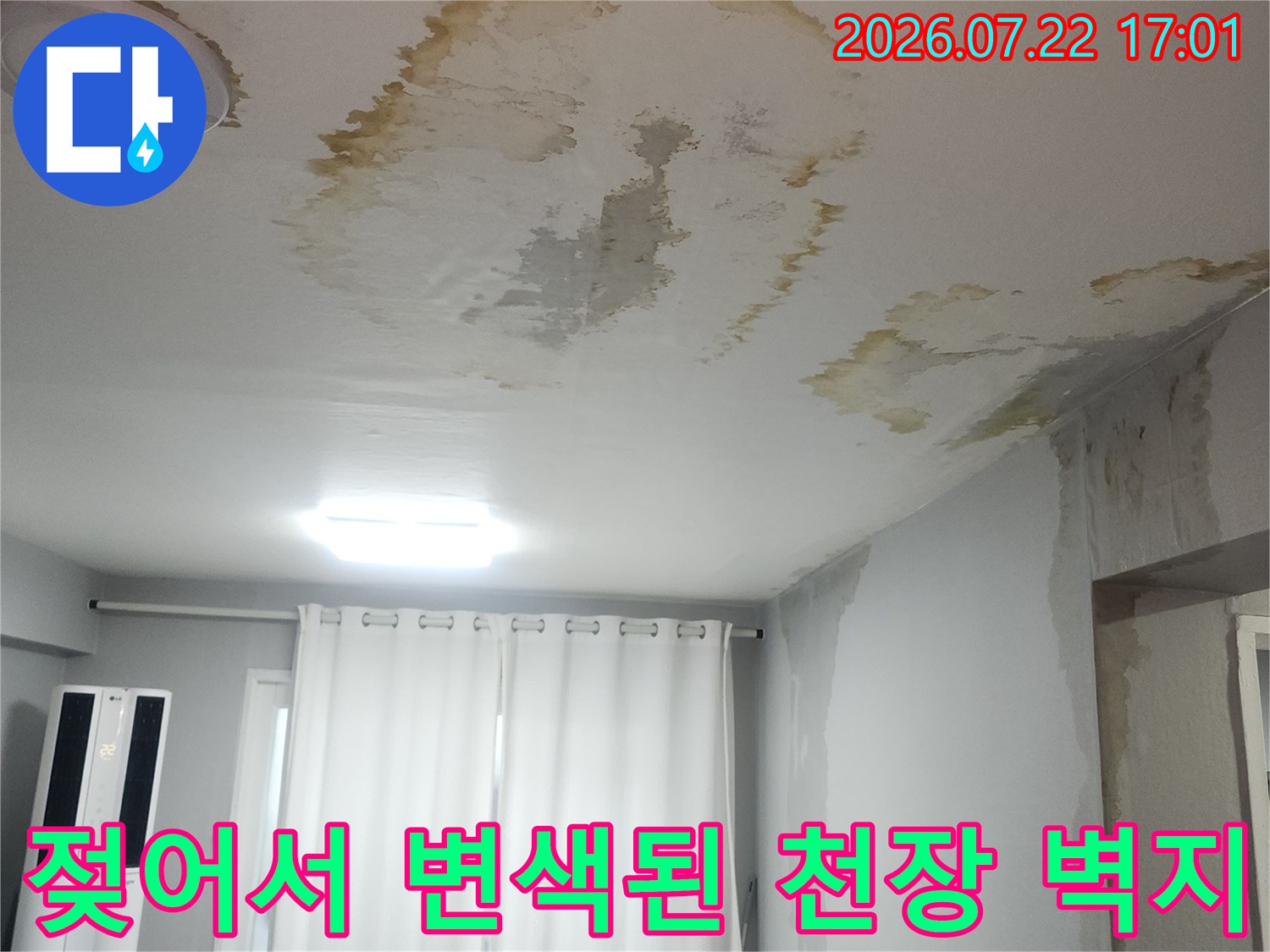 거실 천장 벽지가 물에 젖어 노랗게 변색되고 부풀어 오른 모습
