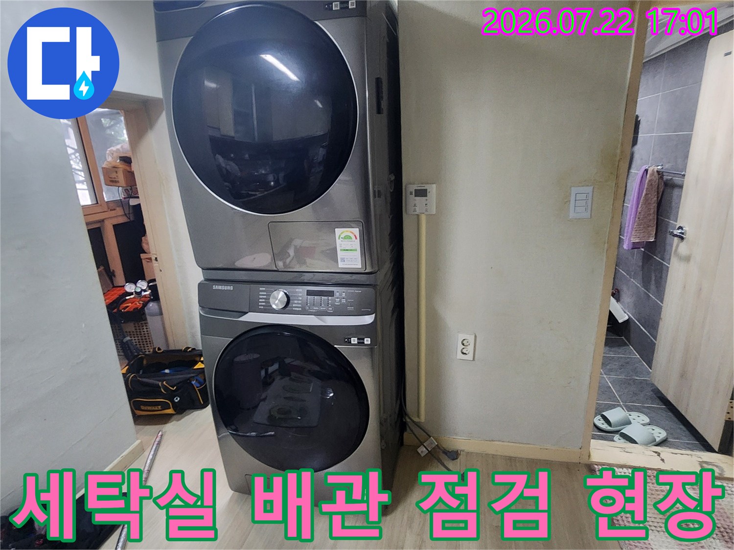 세탁기 옆 벽면 배관과 수도 계량기가 설치된 세탁실 모습