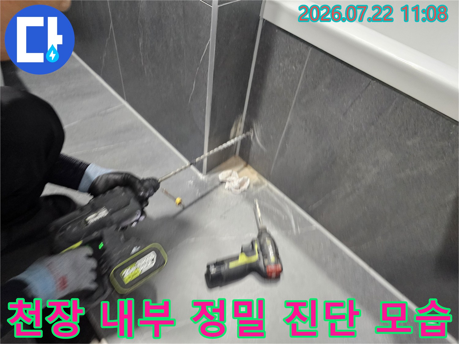 작업자가 전동 공구를 사용하여-천장 마감재 안쪽의 배관 상태를 살피는 장면