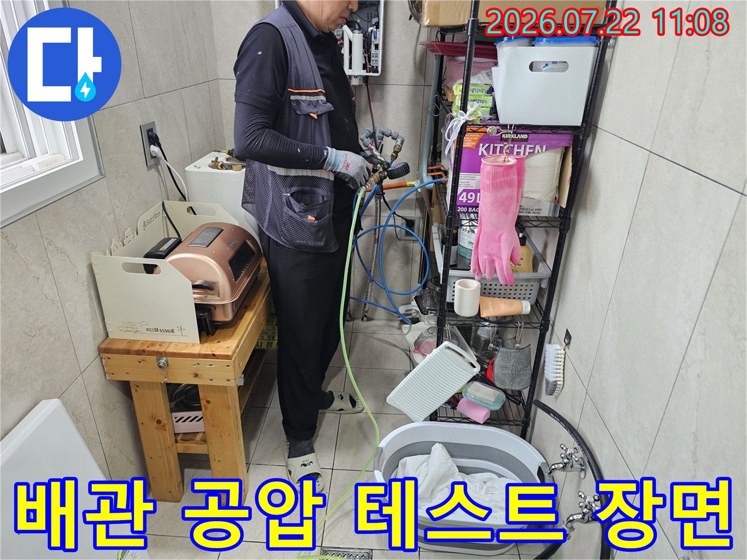 작업자가 파란색과 노란색 호스를 연결하여 배관 압력 검사를 진행하는 모습
