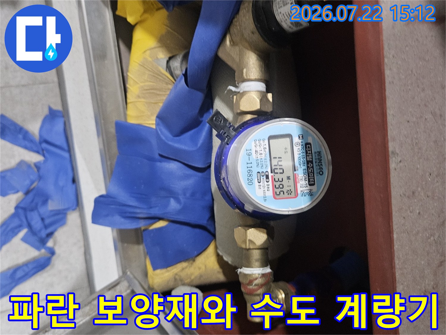 배관 보호를 위해 파란색 테이프가 둘러진 상태에서 확인 중인 수도 계량기 사진