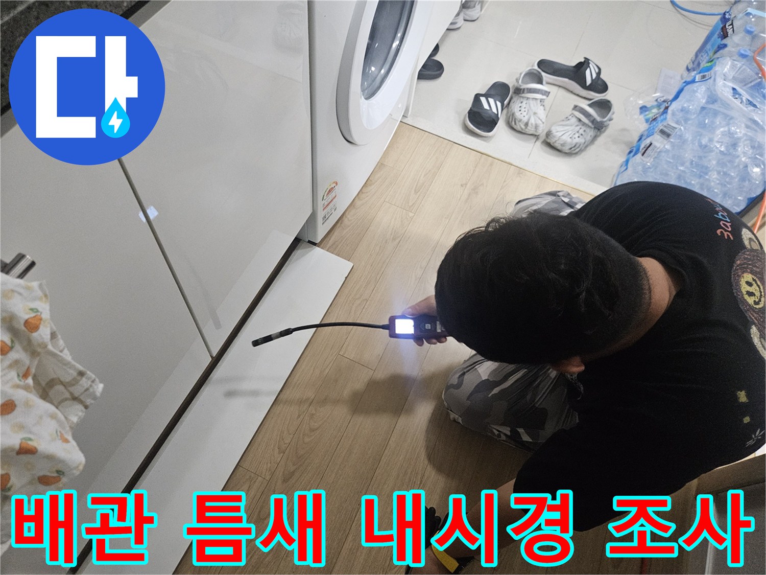 싱크대 하부장 공간에 내시경 카메라를 넣어 배관 상태를 확인하는 작업자
