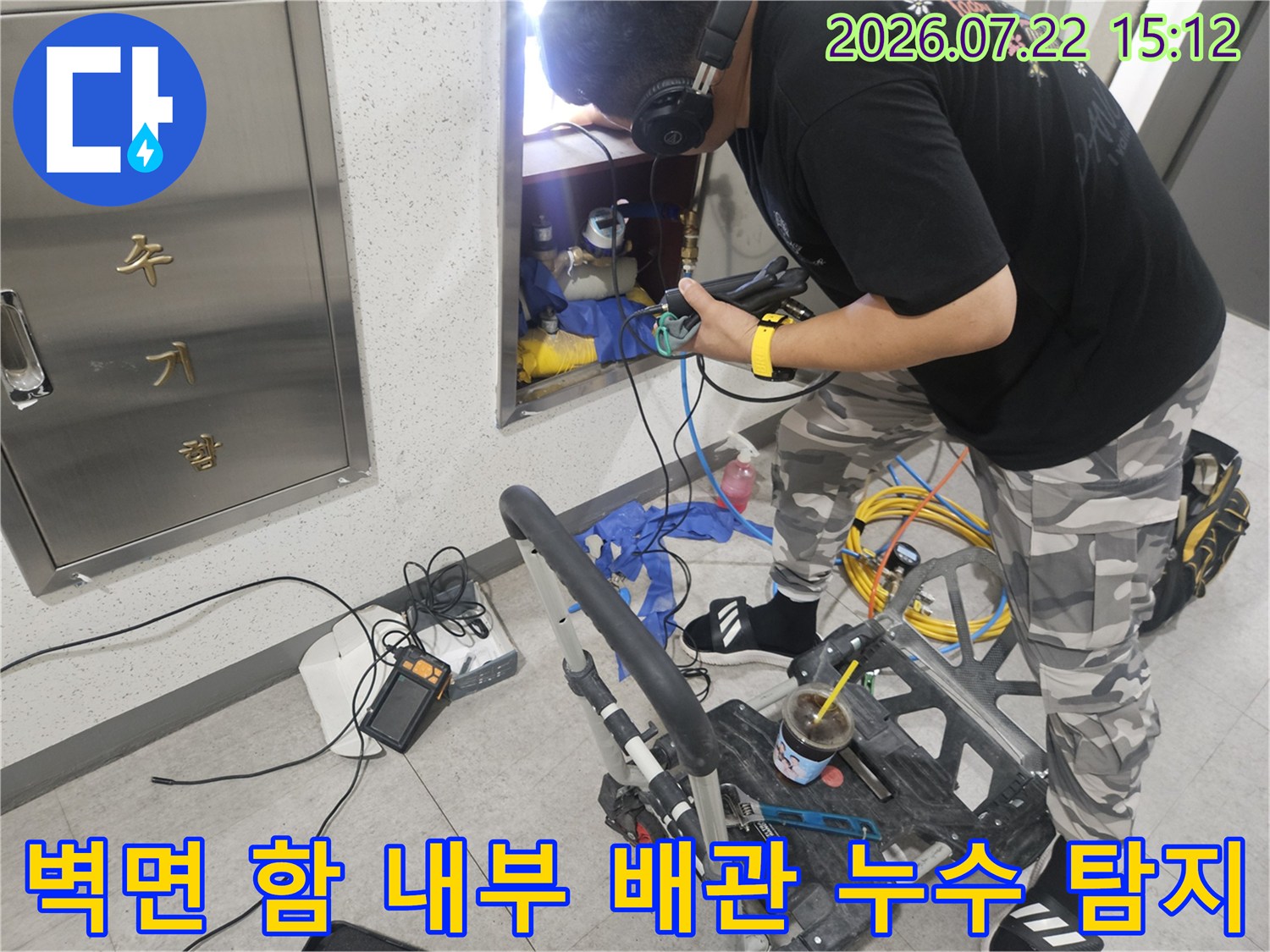 작업자가 헤드셋을 쓰고 가스 탐지기를 사용하여 벽 속 배관의 누출 부위를 찾는 모습