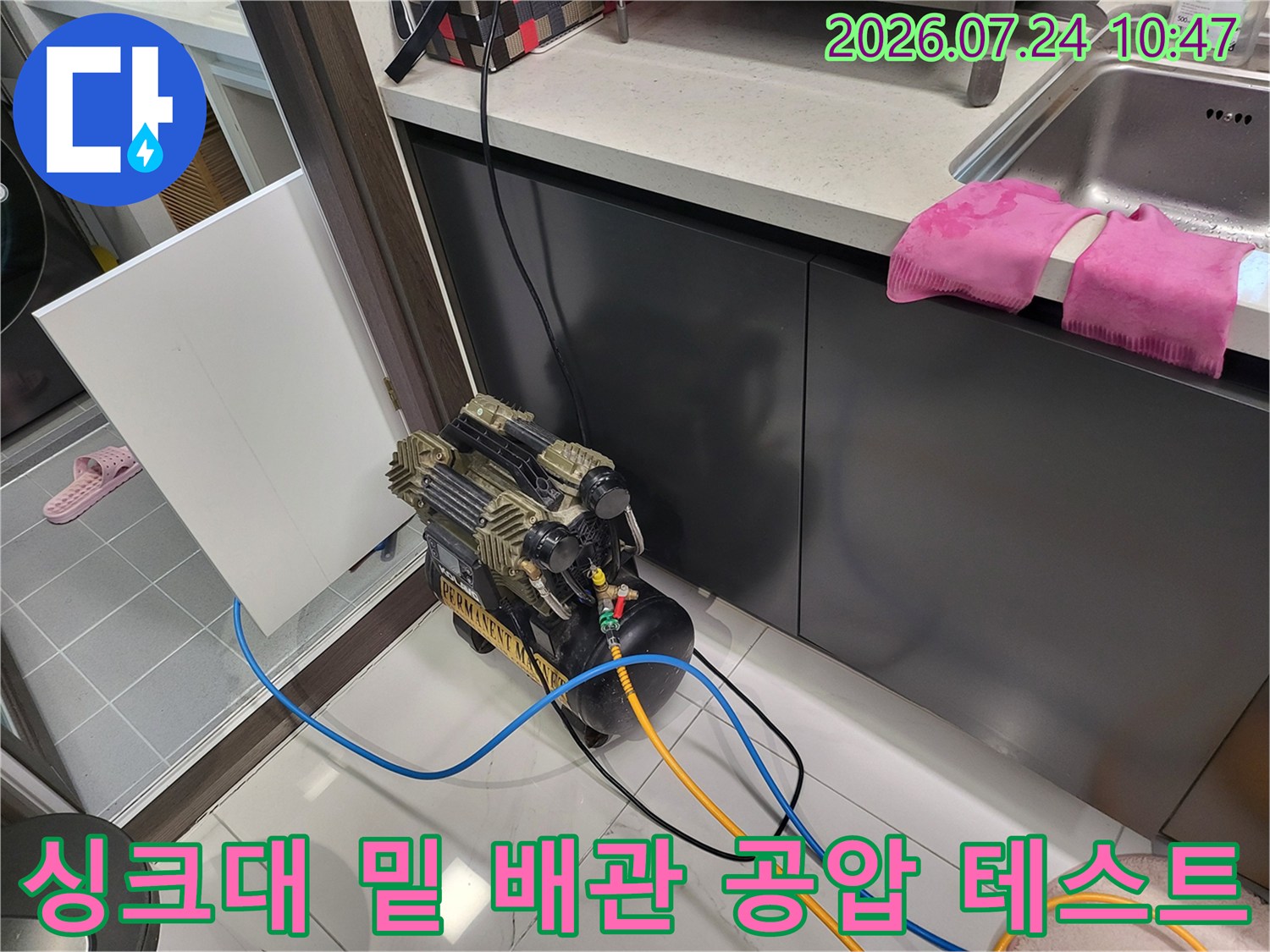 공압 게이지와 연결된 호스를 싱크대 하부 노출 배관에 연결하여 점검하는 모습