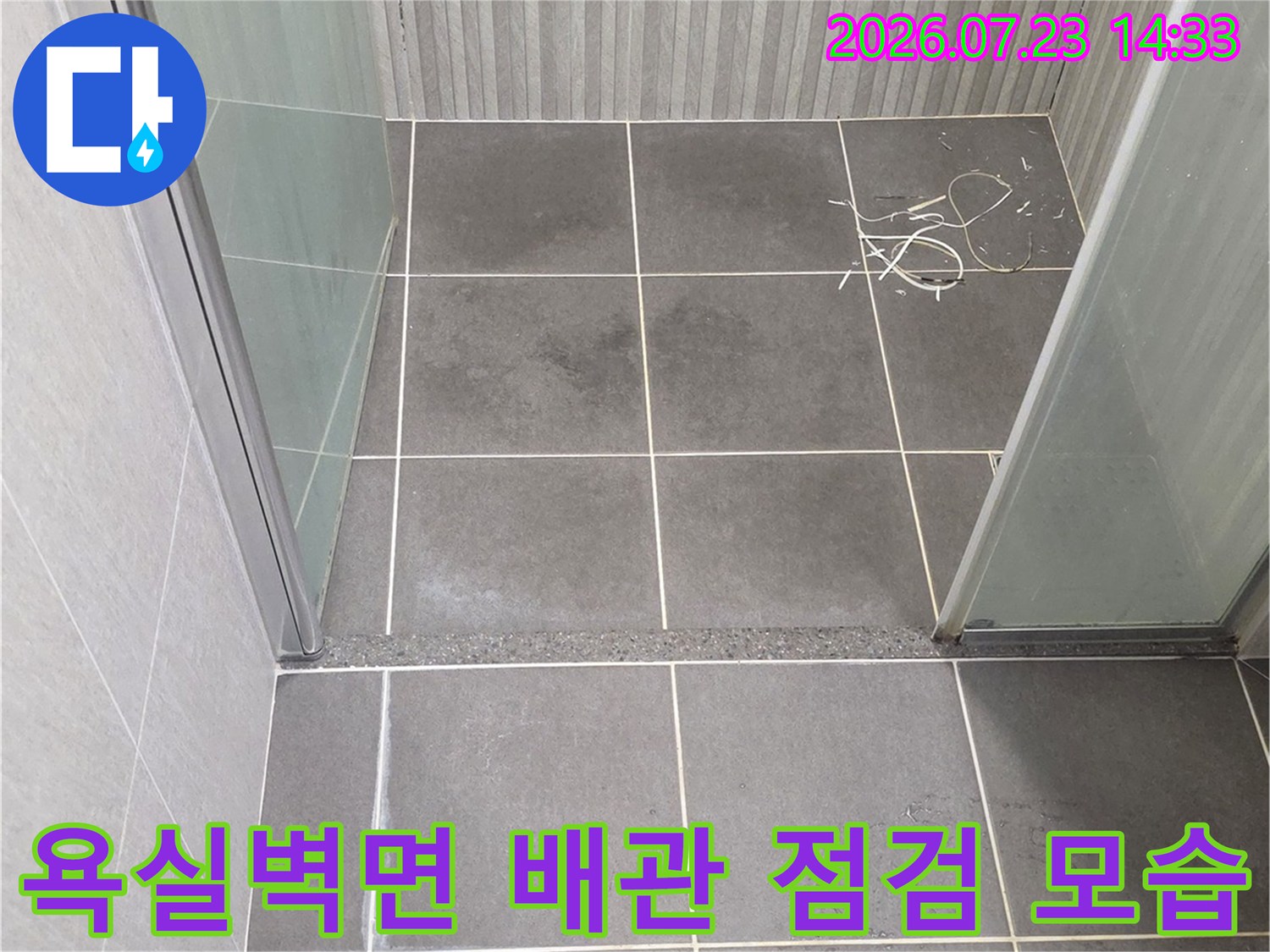 회색 타일 벽면에 설치된 수전 배관과 파란색 손잡이 렌치 도구-누수 진단 과정