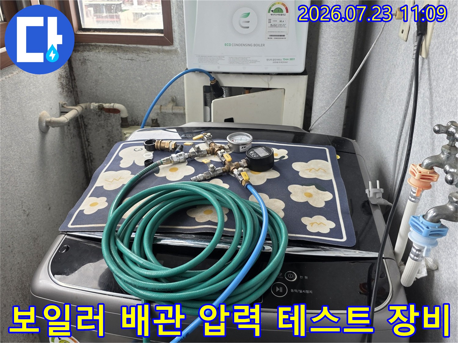 세탁기 위에 놓인 파란색 호스와 게이지가 연결된 누수 정밀 진단 장비