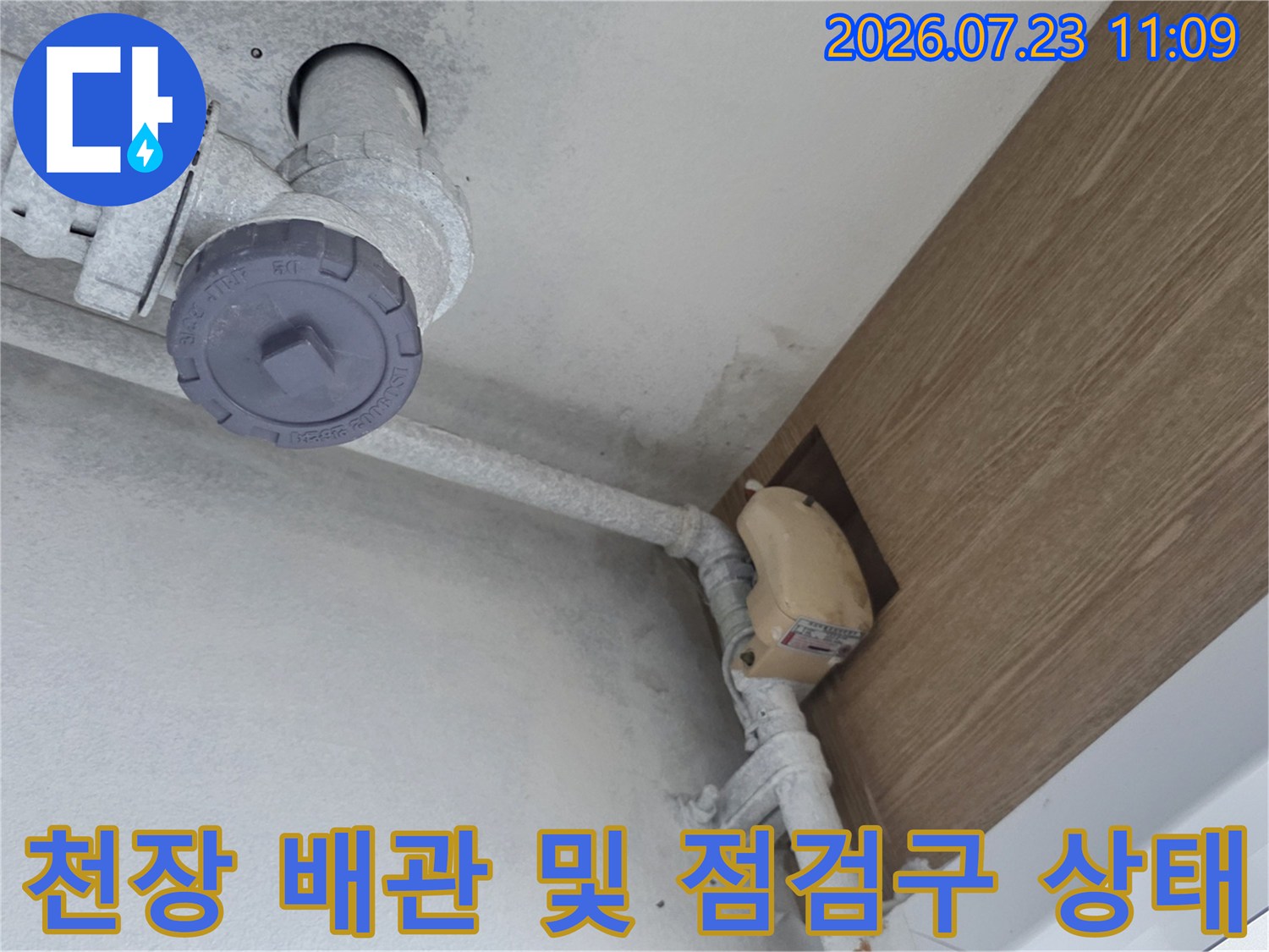 아파트 천장 내부에 설치된 회색 배관과 점검구를 통해 누수 지점을 확인하는 모습