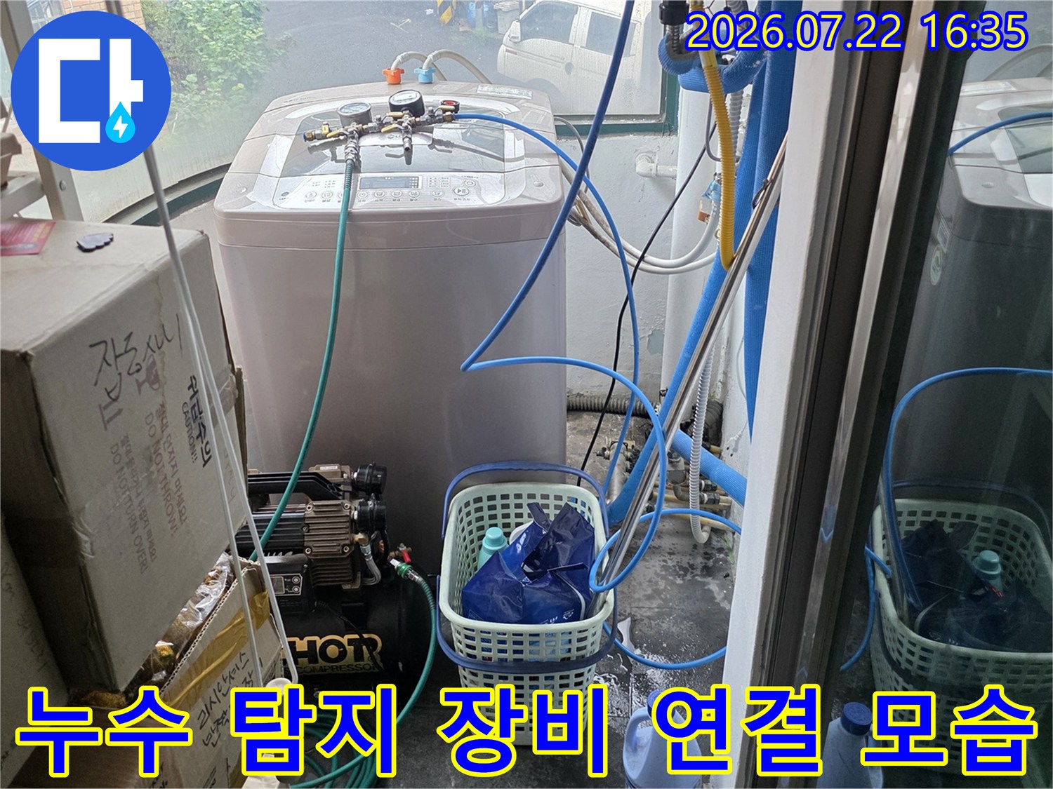 다용도실에서 배관 압력 테스트를 위해 연결된 누수 탐지 장비와 파란색 호스들