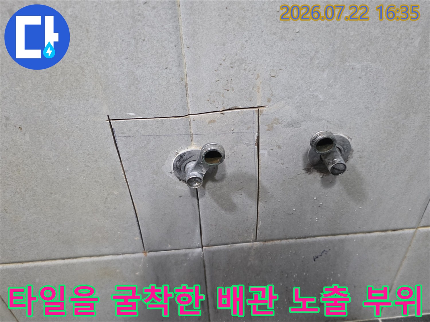 밝은색 타일 벽면을 사각형으로 절개하여 내부의 금속 수도 배관 연결부가 드러난 모습