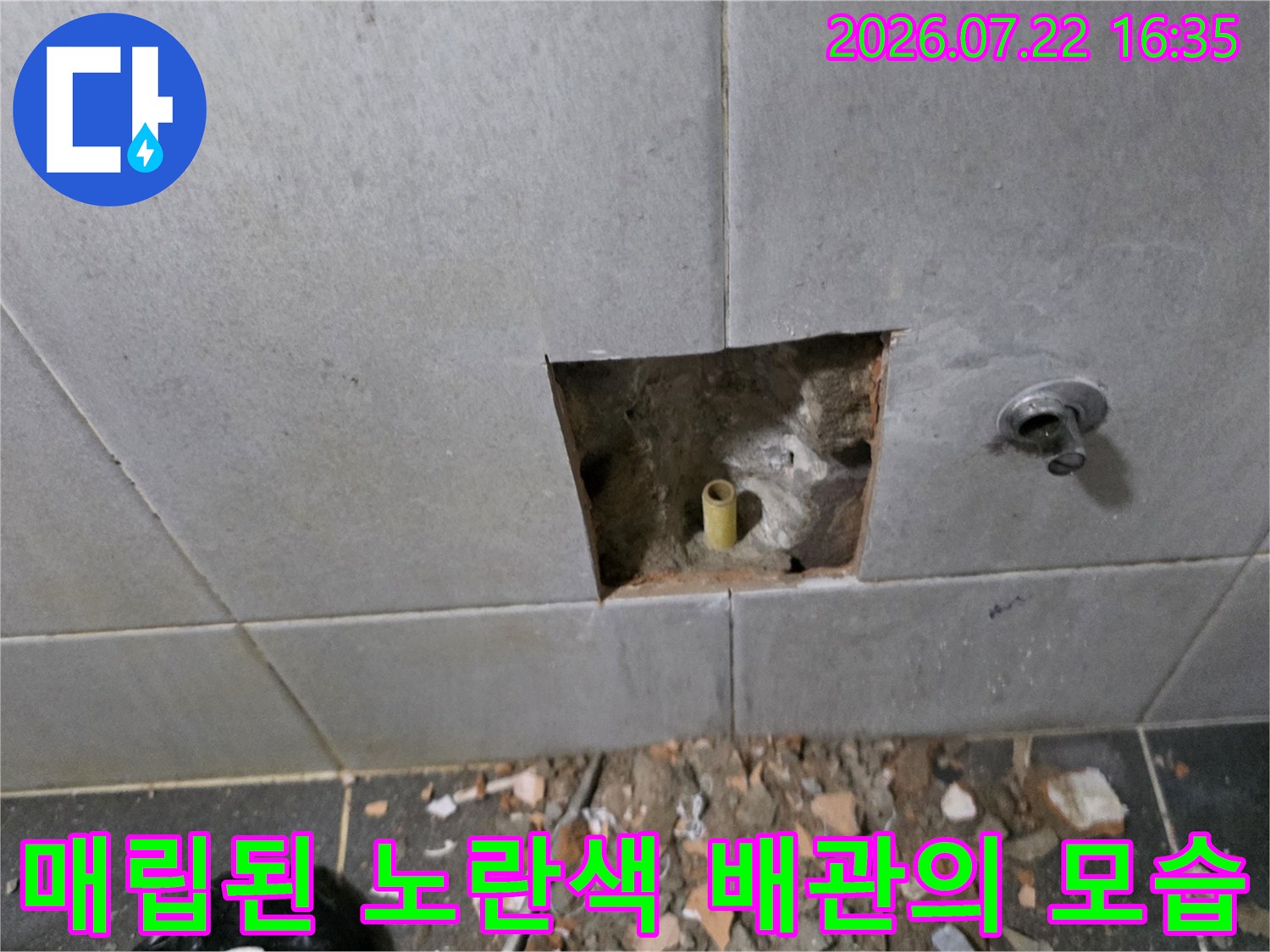 벽면 타일을 걷어내고 드러난 노후된 노란색 PPC 수도 배관과 주변 시멘트 벽면