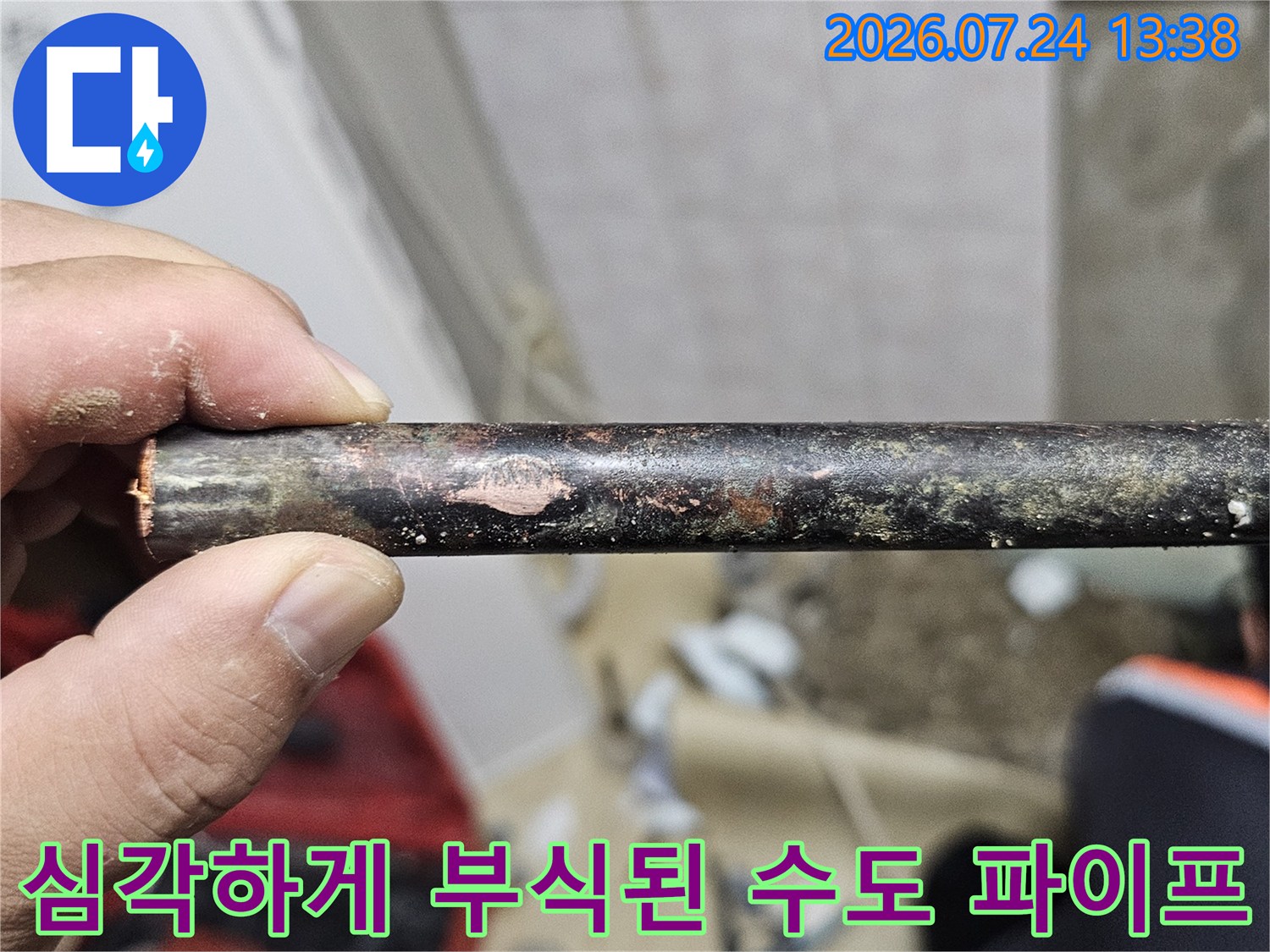 손에 쥐어진 검은색과 갈색으로 부식된 노후된 금속 배관의 모습