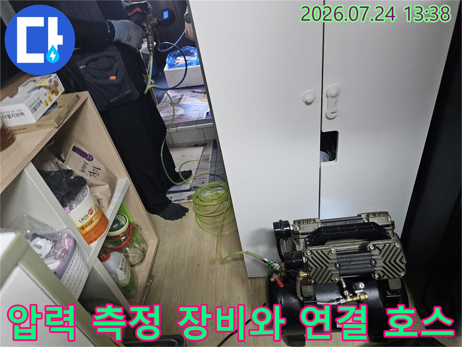 실내 바닥에 설치된 누수 탐지 기계와 길게 늘어진 초록색 배관 호스