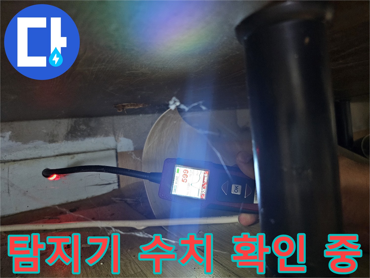 싱크대 밑 공간에서 가스 탐지기로 누수 반응을 측정하는 모습입니다.