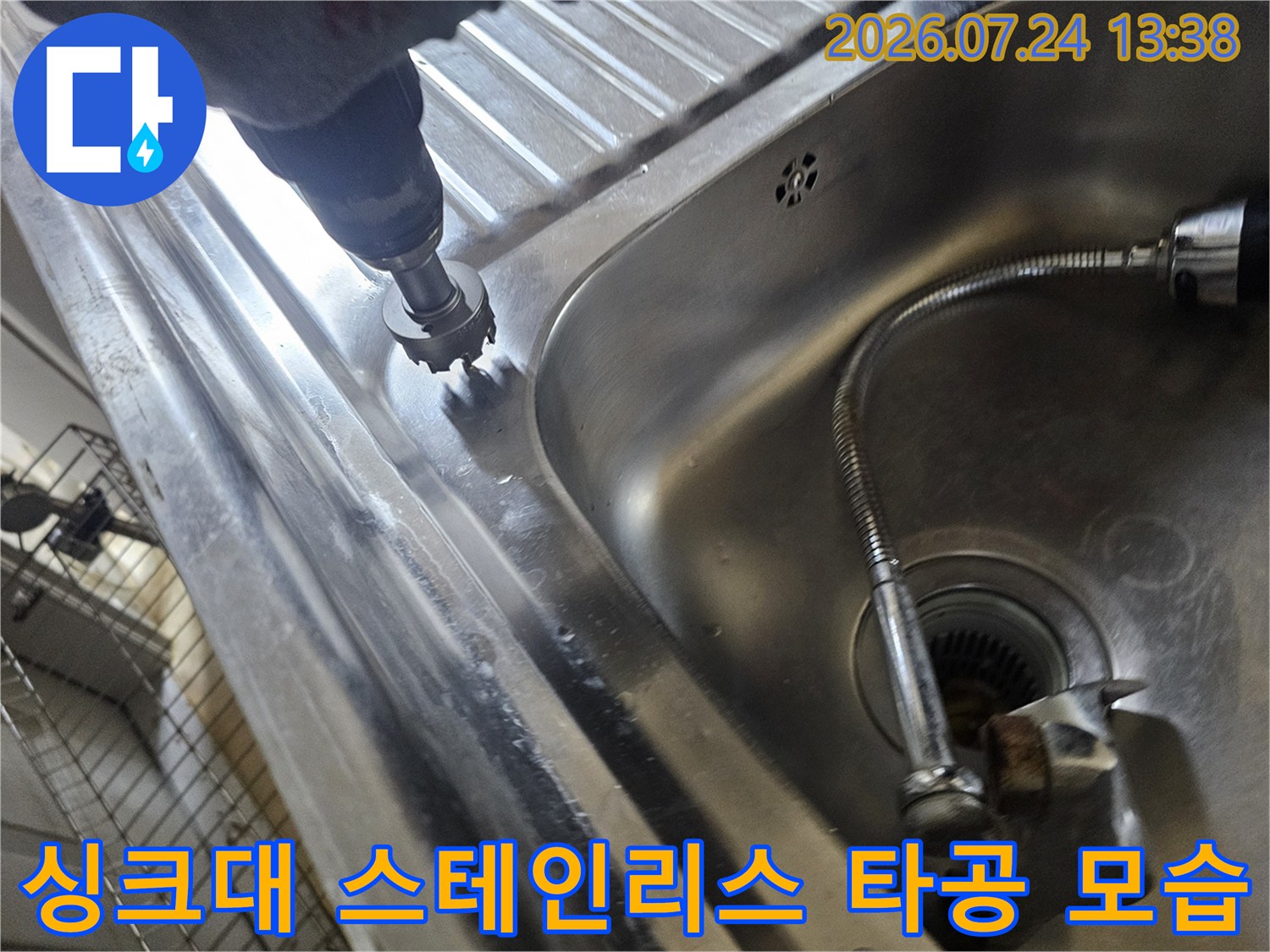 싱크대 볼 옆쪽 금속 상판에 구멍을 뚫어 내부 배관으로 진입하려는 작업 사진