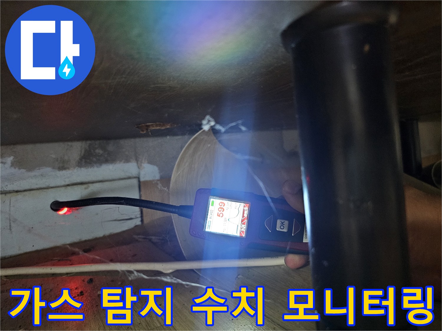 싱크대 아래 좁은 공간에서 가스 누출 수치를 확인하는 모습입니다.