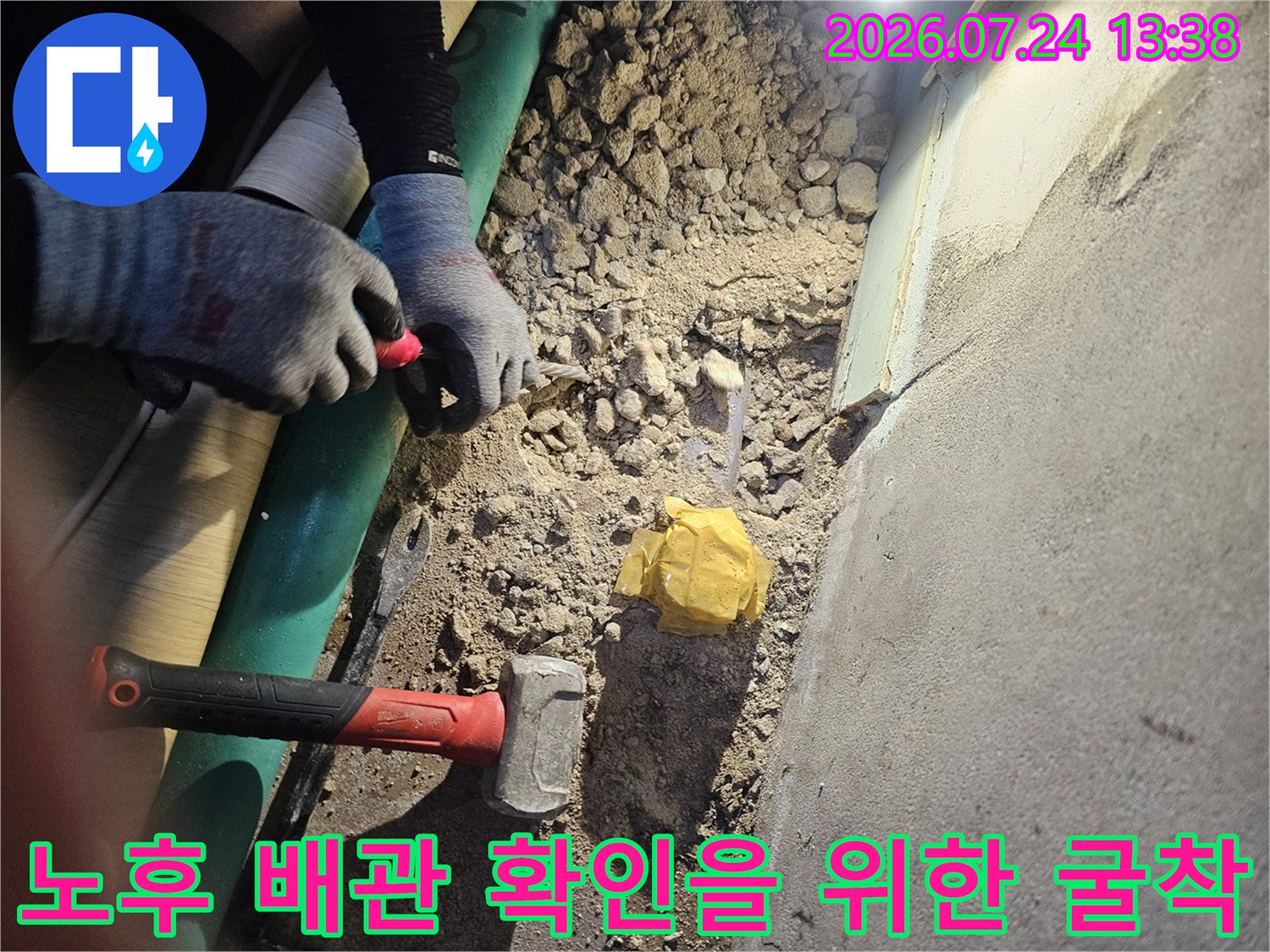 작업 도구와 장갑이 보이며 바닥면이 파헤쳐진 누수 공사 현장 사진