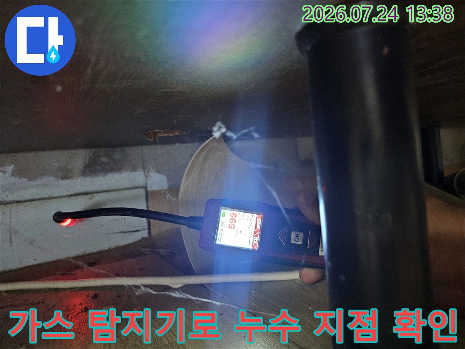 좁은 가구 하단 공간에서 가스 탐지기를 사용해 누수 지점을 추적하는 모습