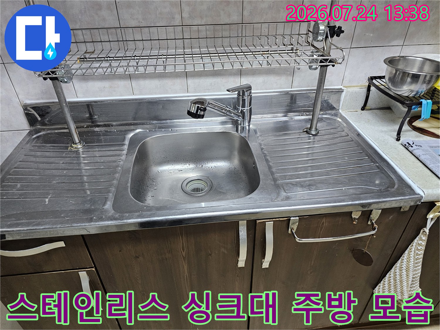 주방 조리대 위에 설치된 스테인리스 싱크볼과 수전 그리고 상단 건조망